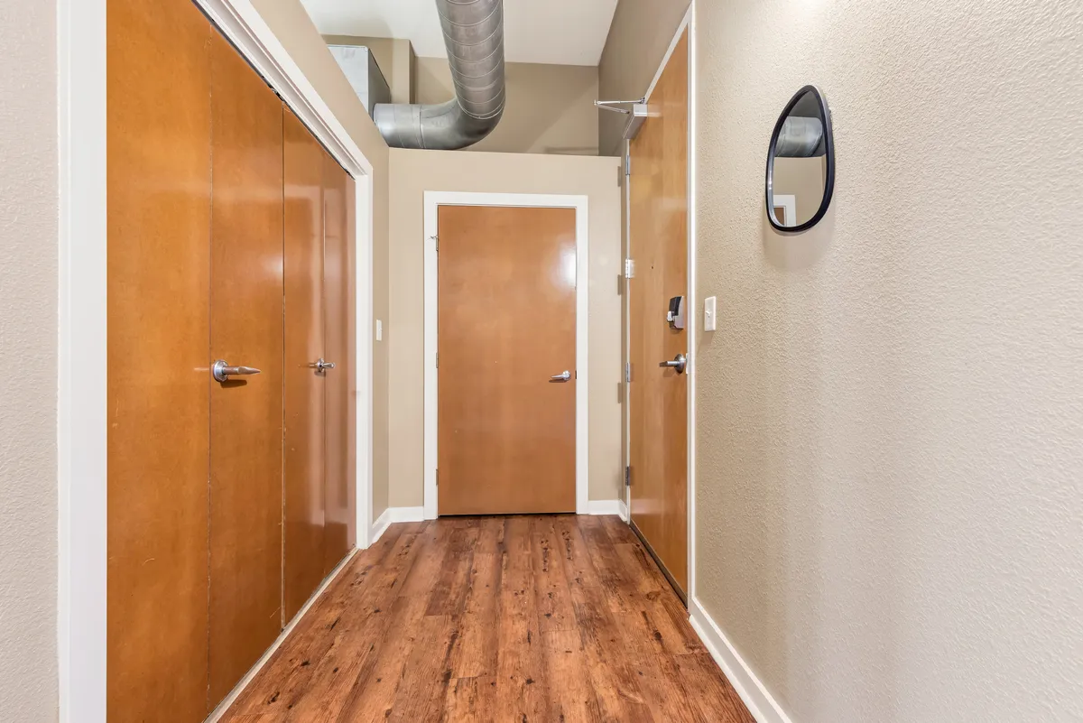 This scene shows a welcoming entryway with stylish wooden doors, a mirror, quality flooring, and visible ventilation ductwork. It’s a transition space where guests are greeted, coats are hung, and shoes are stored—an area that bridges the home and the world outside.